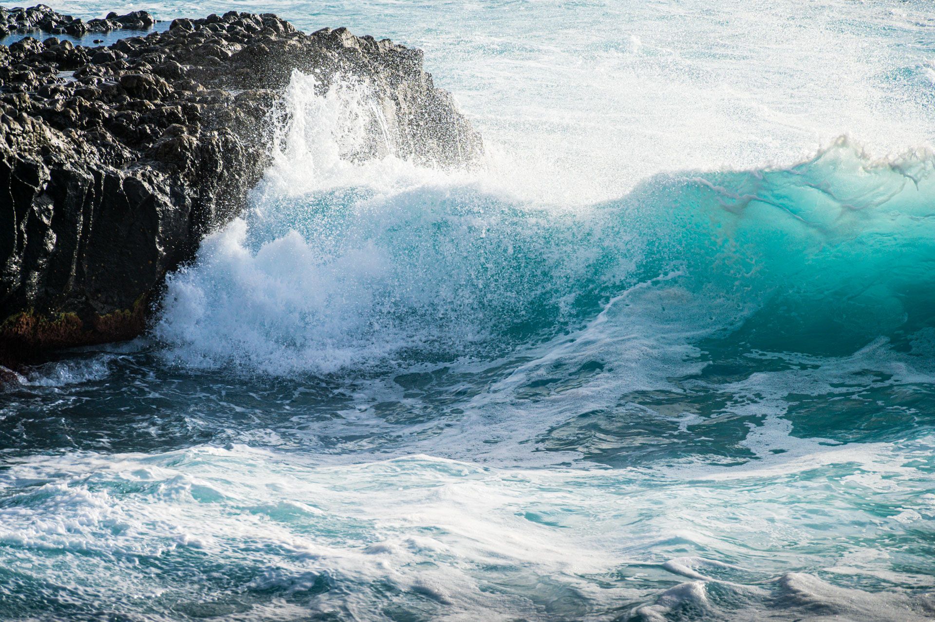 türkisfarbene Welle am Felsen
