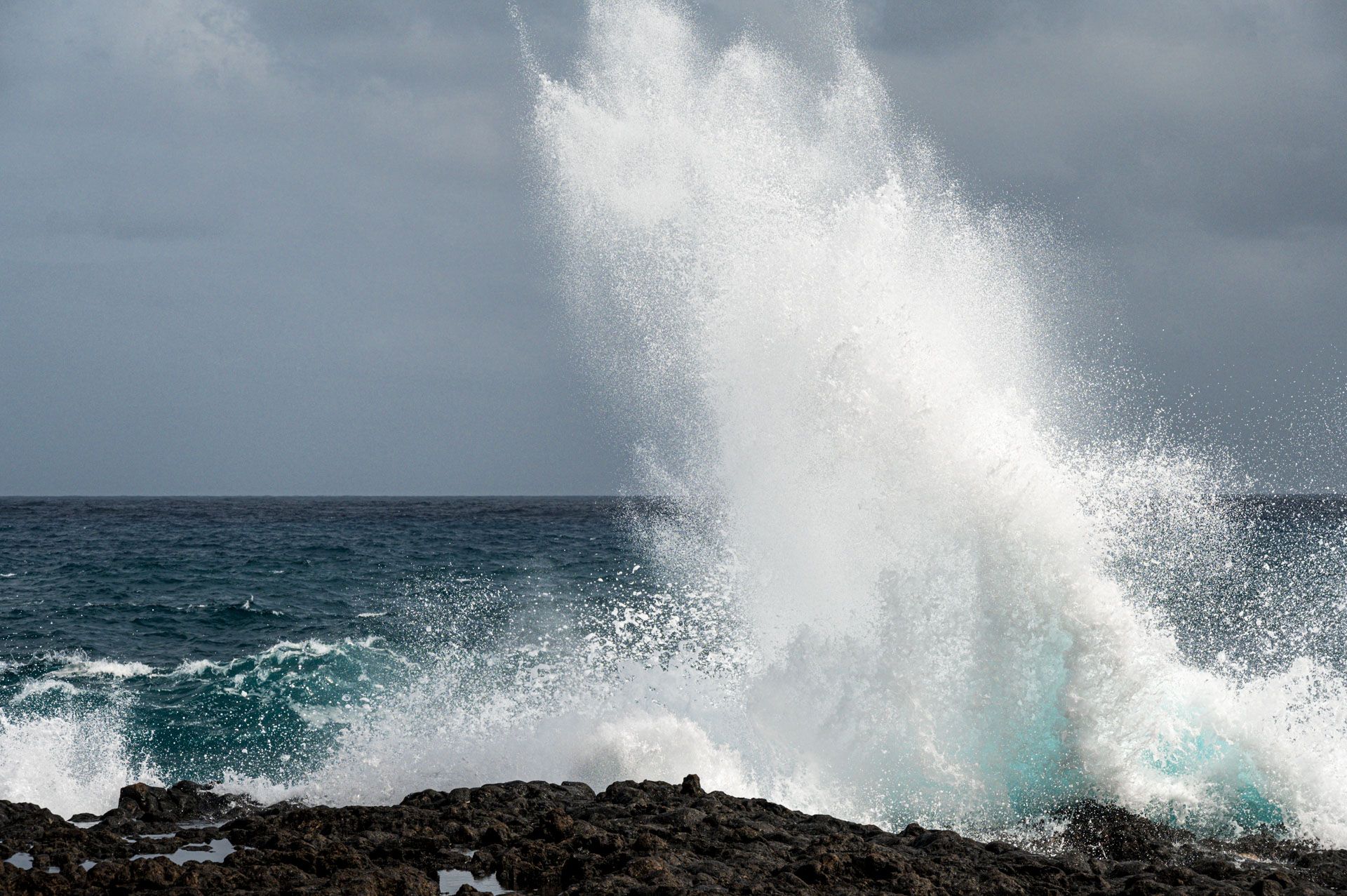 Welle bricht am Fels